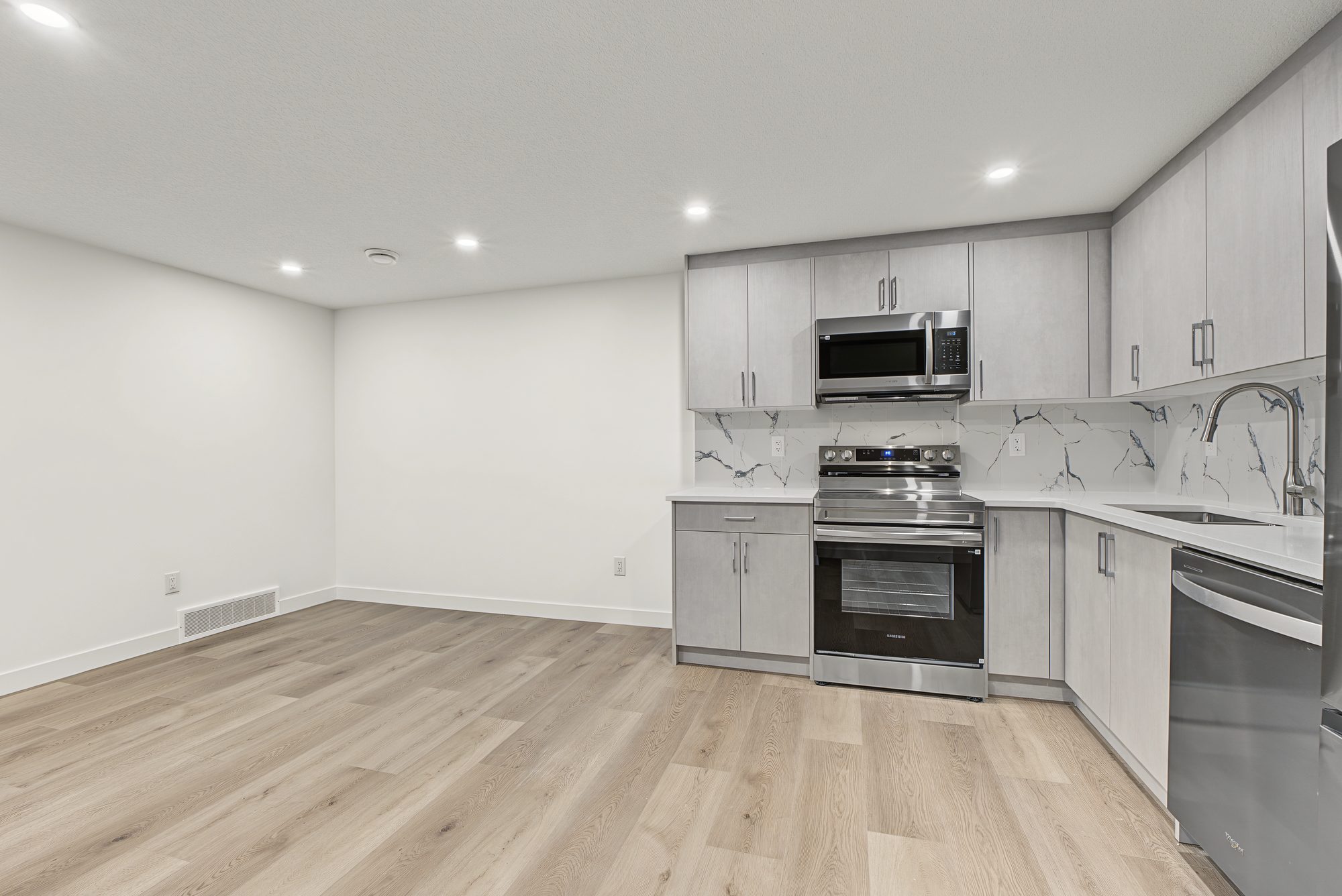 Finished legal basement suite living room with vinyl plank floor and pot lights